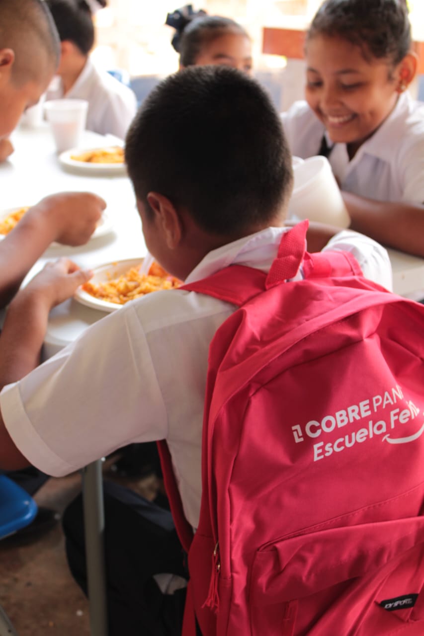 Estudiantes recibiendo mochilas escolares del Proyecto Escuela Feliz en una escuela de Colón